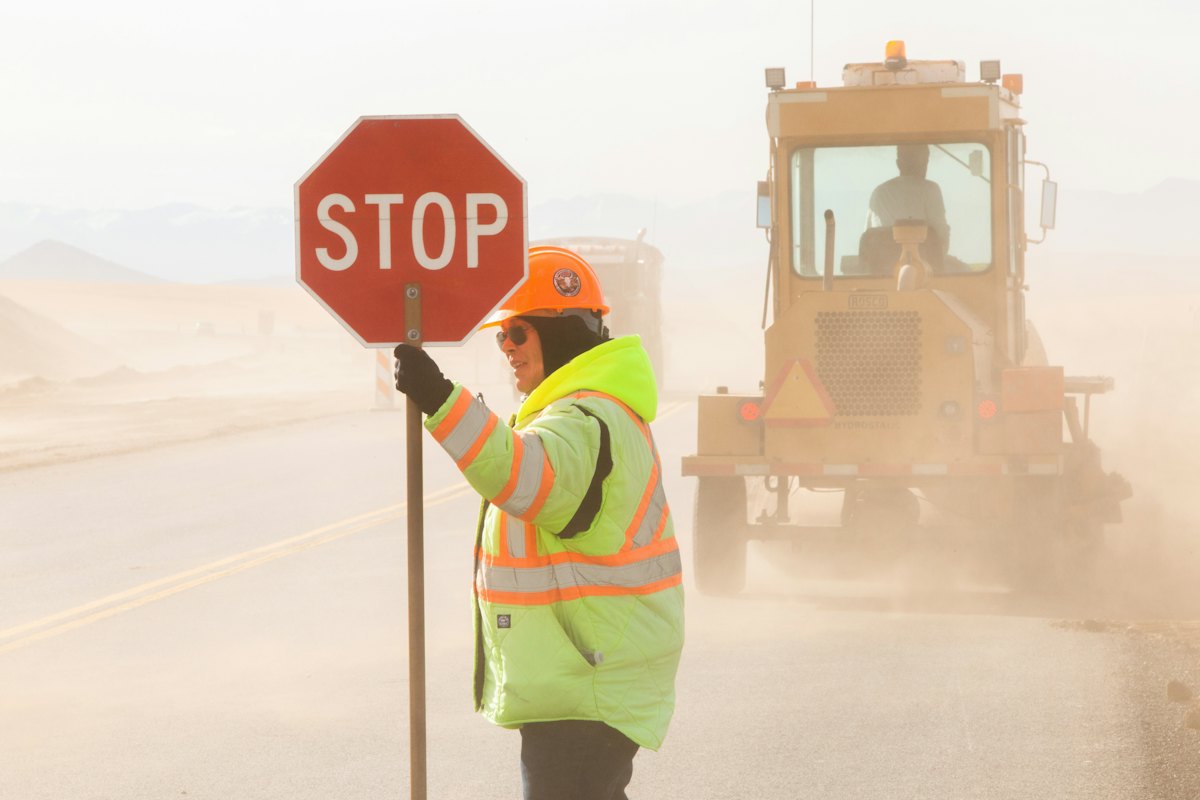 Flagger in a high-visibility vest holding a STOP paddle to hold traffic at a work zone