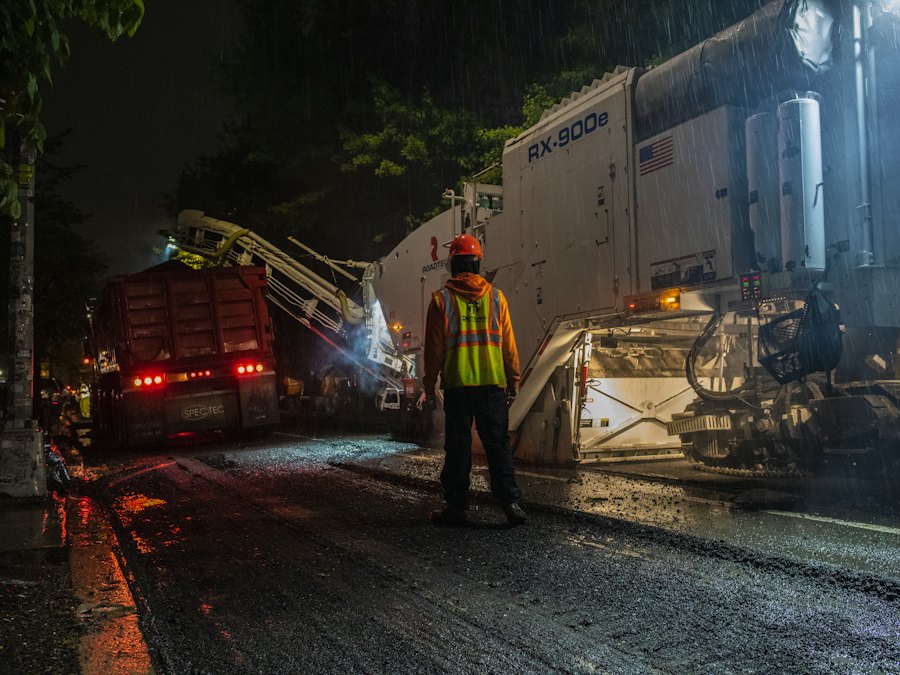 Night work zone lit by truck-mounted lights with a worker in reflective gear