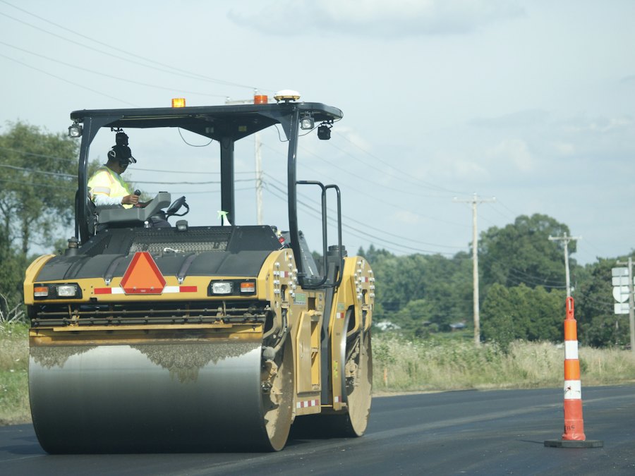 Roller and paving equipment working a closed lane marked with a traffic cone